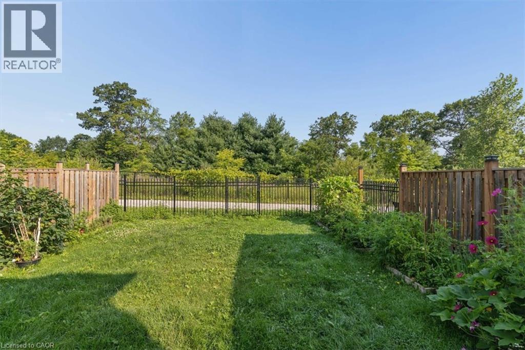 Expansive backyard featuring a manicured lawn, wood fencing, and perimeter plantings - 242 Moorlands Crescent, Kitchener, ON - Outdoor