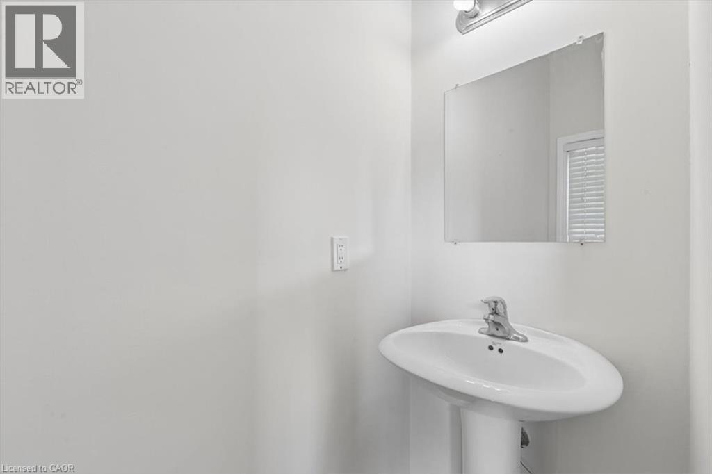 Pedestal sink with a polished chrome faucet, rectangular wall mirror, and overhead vanity light - 242 Moorlands Crescent, Kitchener, ON - Indoor Photo Showing Bathroom