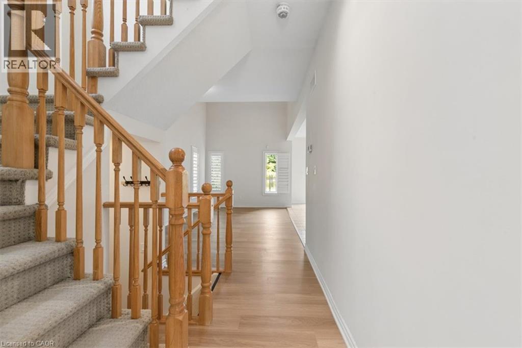 Hardwood-finish flooring, staircase with natural wood railing, carpeted stair treads, interior window shutters, and white wall finishes - 242 Moorlands Crescent, Kitchener, ON - Indoor Photo Showing Other Room