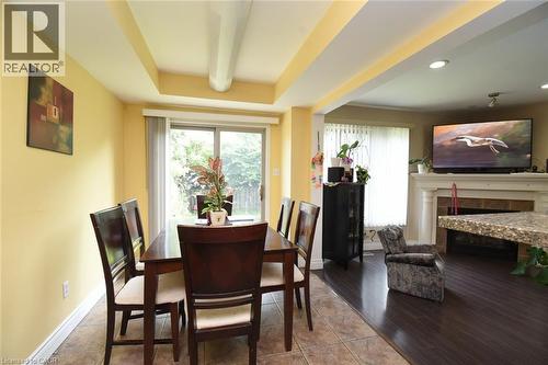 Elegant dining area showcasing warm yellow walls, coffered ceiling with recessed lighting, and dark wood-finish flooring - 509 Southridge Drive, Hamilton, ON - Indoor Photo Showing Dining Room With Fireplace