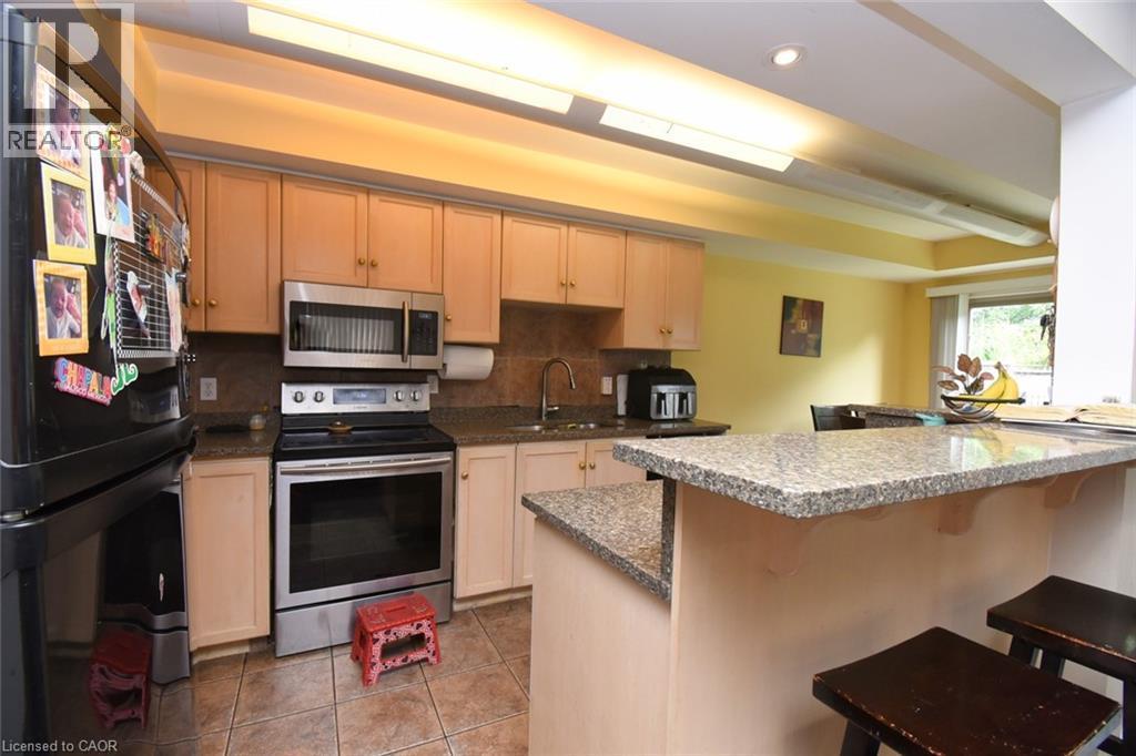 Open-concept kitchen and dining area featuring stainless steel appliances, granite countertops, light wood cabinetry with ample storage, recessed ceiling lighting, and a breakfast bar with seating - 509 Southridge Drive, Hamilton, ON - Indoor Photo Showing Kitchen