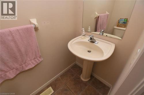 Pedestal sink with chrome-finish faucet, wall-mounted mirror, and tile flooring - 509 Southridge Drive, Hamilton, ON - Indoor Photo Showing Bathroom