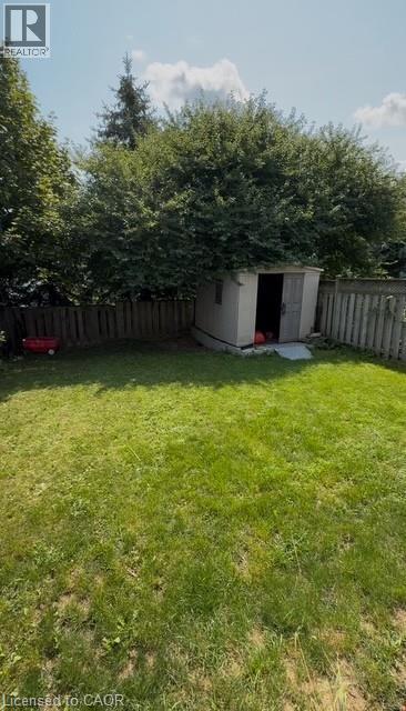 Spacious backyard featuring a manicured lawn, established perimeter trees, and a functional storage shed - 509 Southridge Drive, Hamilton, ON - Outdoor With Backyard