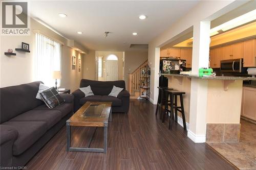 Open-concept living and kitchen area featuring dark wood-finish flooring throughout, a spacious black upholstered sectional sofa, wood coffee table, recessed ceiling lighting, and a kitchen with wood - 509 Southridge Drive, Hamilton, ON - Indoor Photo Showing Living Room