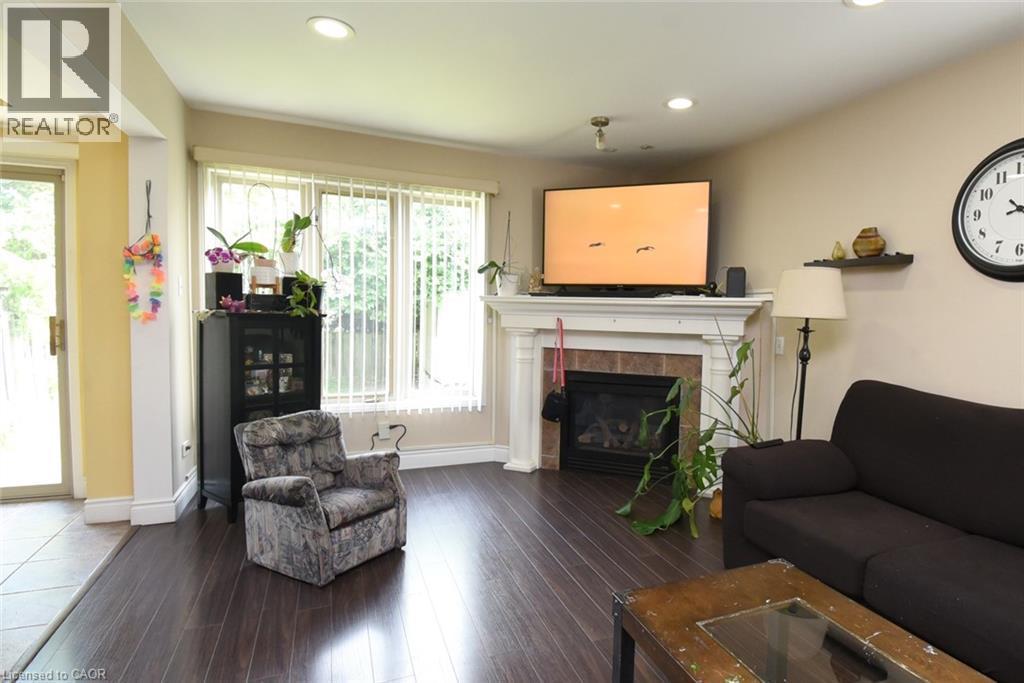 Bright, open living space featuring wood-finish flooring, a fireplace with mantel, built-in media shelving, recessed ceiling lighting, and abundant natural light from multiple windows and glass doors - 509 Southridge Drive, Hamilton, ON - Indoor Photo Showing Living Room With Fireplace