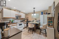 Kitchen with white upper and lower cabinetry, white appliances, and a tile backsplash -