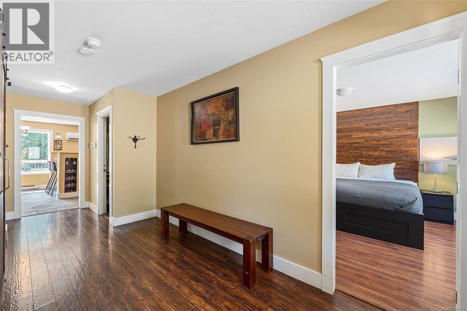 Wood-finish laminate flooring throughout, warm-toned wall paint, and white trim accents. Staircase still present under the stairs to access downstairs if one wished to open it up again. - 4105 Ross Rd, Nanaimo, BC - Indoor