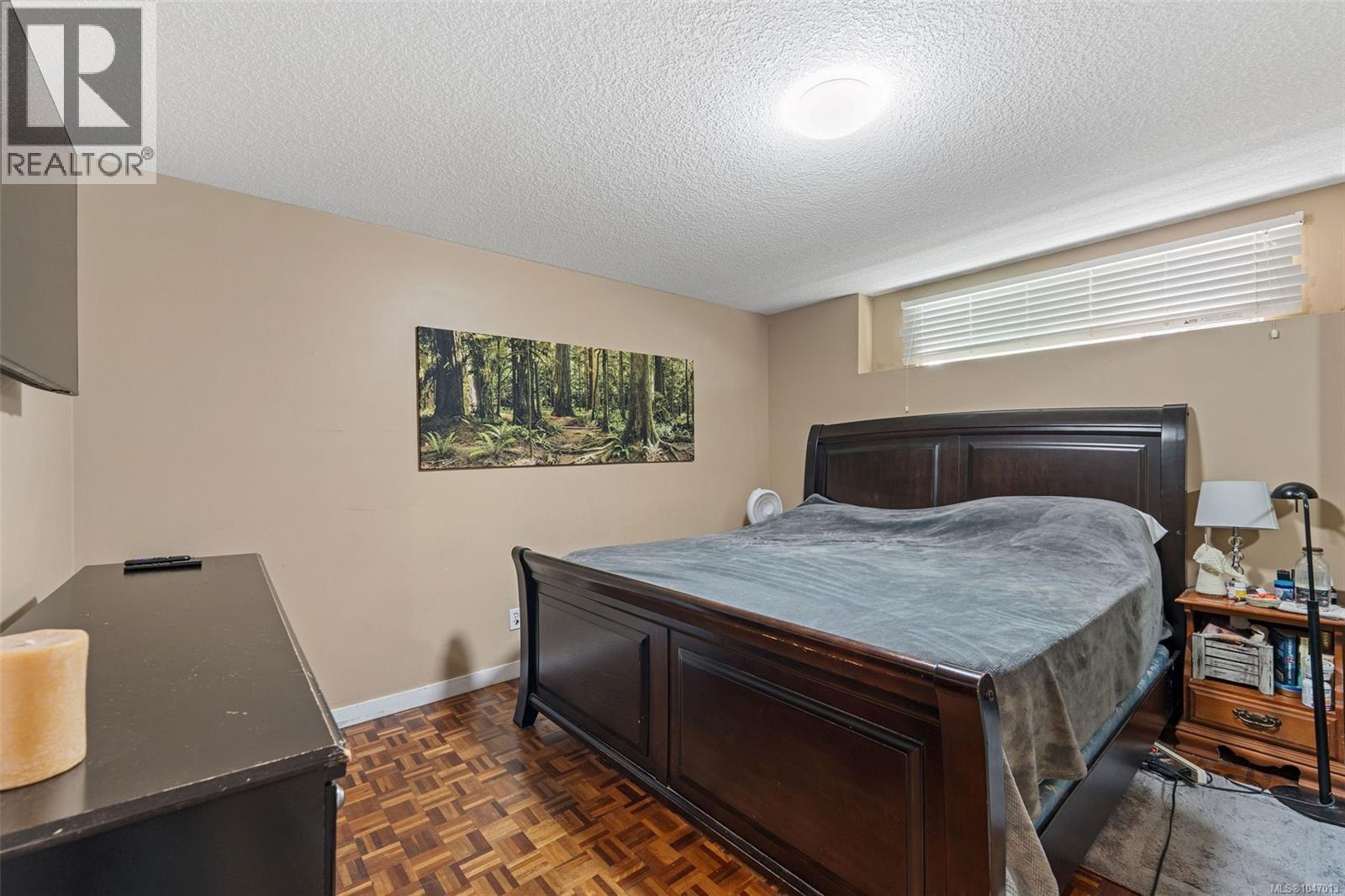 Downstairs Master Bedroom. Recessed window with horizontal blinds, wood-finish flooring, and neutral wall tones - 4105 Ross Rd, Nanaimo, BC - Indoor Photo Showing Bedroom