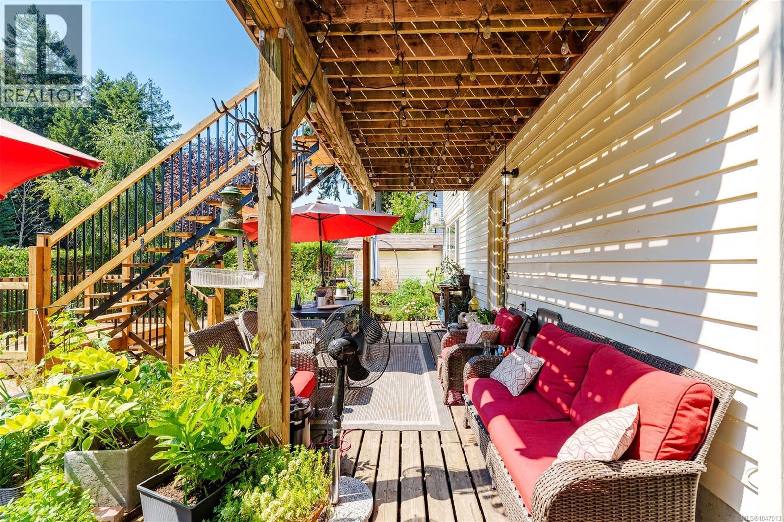 Access to suite entrance. Covered outdoor patio with wood decking, exterior siding, and a brand new wooden staircase with black metal balusters - 4105 Ross Rd, Nanaimo, BC - Outdoor With Deck Patio Veranda