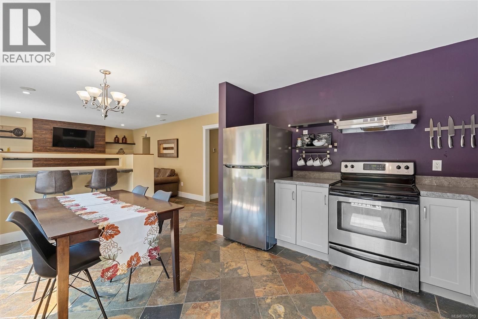Stainless steel appliances, built-in shelving, stone tile flooring, and a breakfast bar with built-in seating - 4105 Ross Rd, Nanaimo, BC - Indoor Photo Showing Kitchen