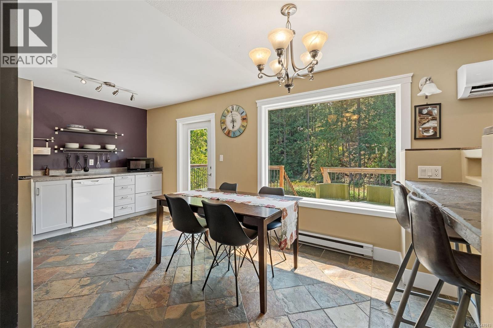Spacious kitchen featuring slate flooring, white cabinetry, a large picture window, and a built-in breakfast bar - 4105 Ross Rd, Nanaimo, BC - Indoor Photo Showing Dining Room