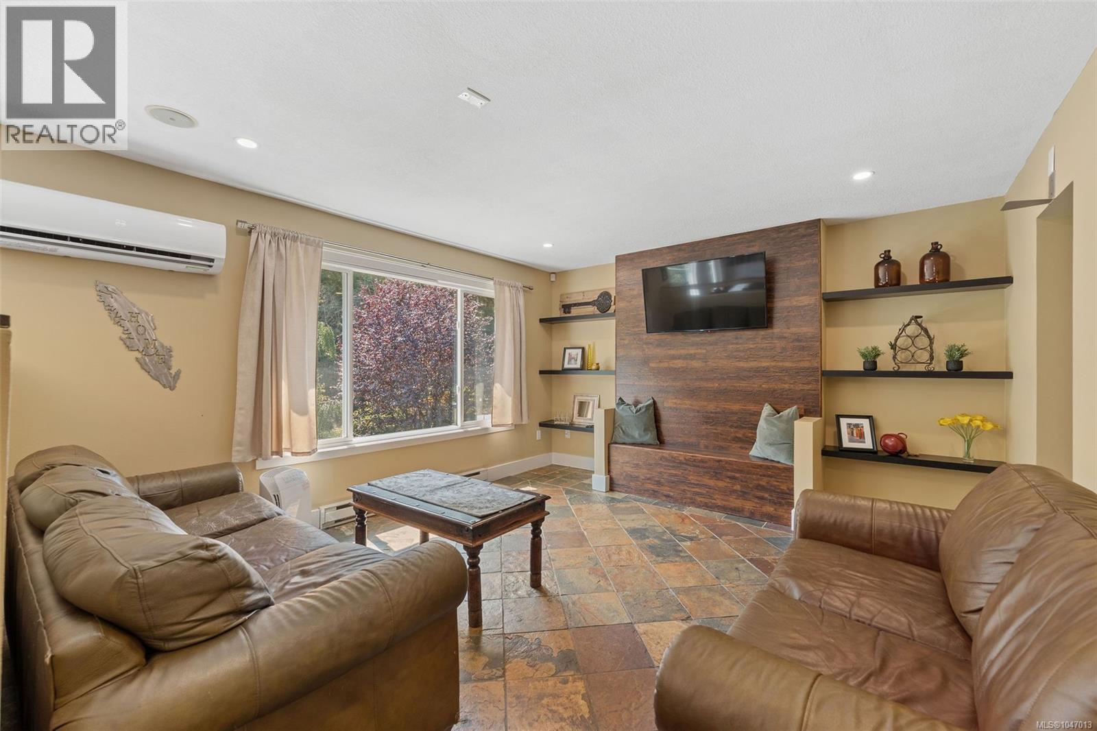 Recessed lighting, wood-finish accent wall, built-in shelving, stone tile flooring, and large window - 4105 Ross Rd, Nanaimo, BC - Indoor Photo Showing Living Room With Fireplace
