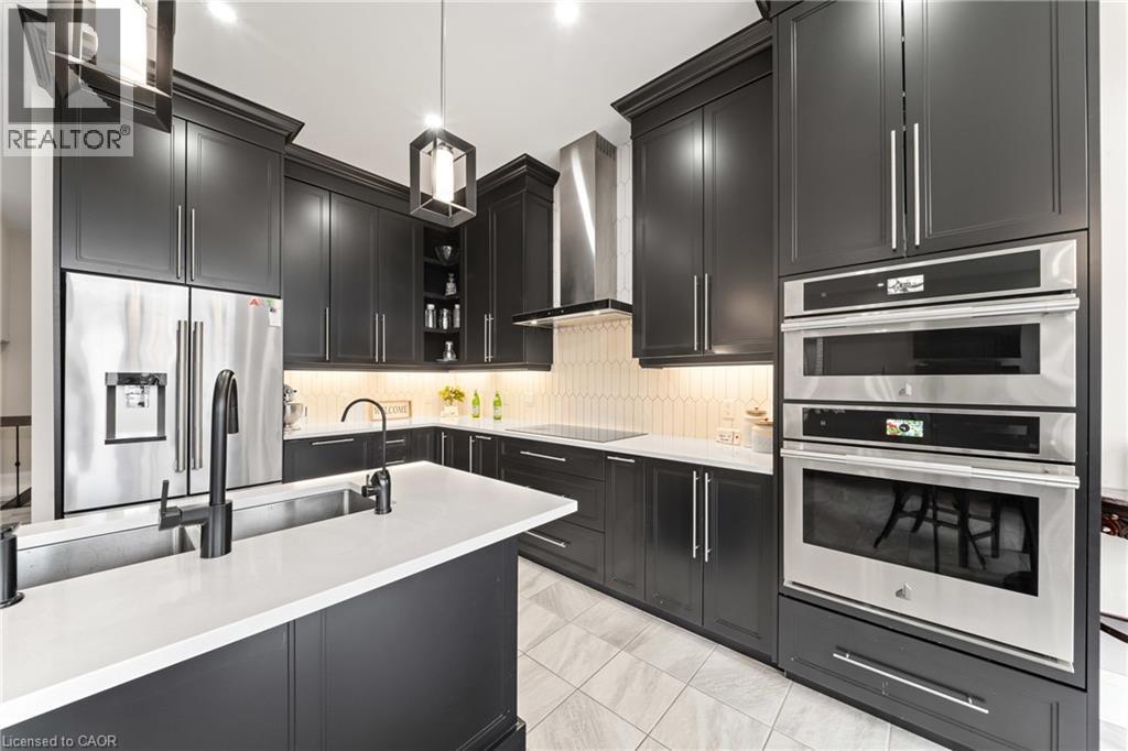 Modern kitchen featuring dark cabinetry, white countertops, stainless steel appliances, a built-in wall oven, and pendant lighting - 130 Pondcliffe Drive, Kitchener, ON - Indoor Photo Showing Kitchen With Upgraded Kitchen