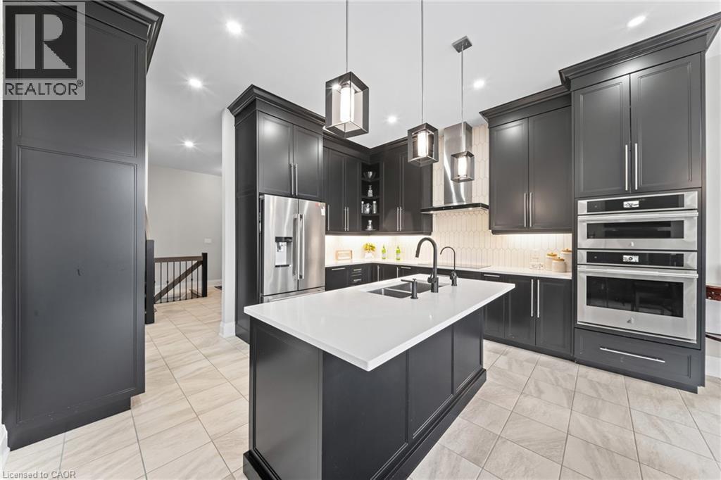 Gourmet kitchen featuring dark cabinetry, stainless steel appliances, a center island with a white countertop, recessed lighting, and tile flooring - 130 Pondcliffe Drive, Kitchener, ON - Indoor Photo Showing Kitchen With Upgraded Kitchen