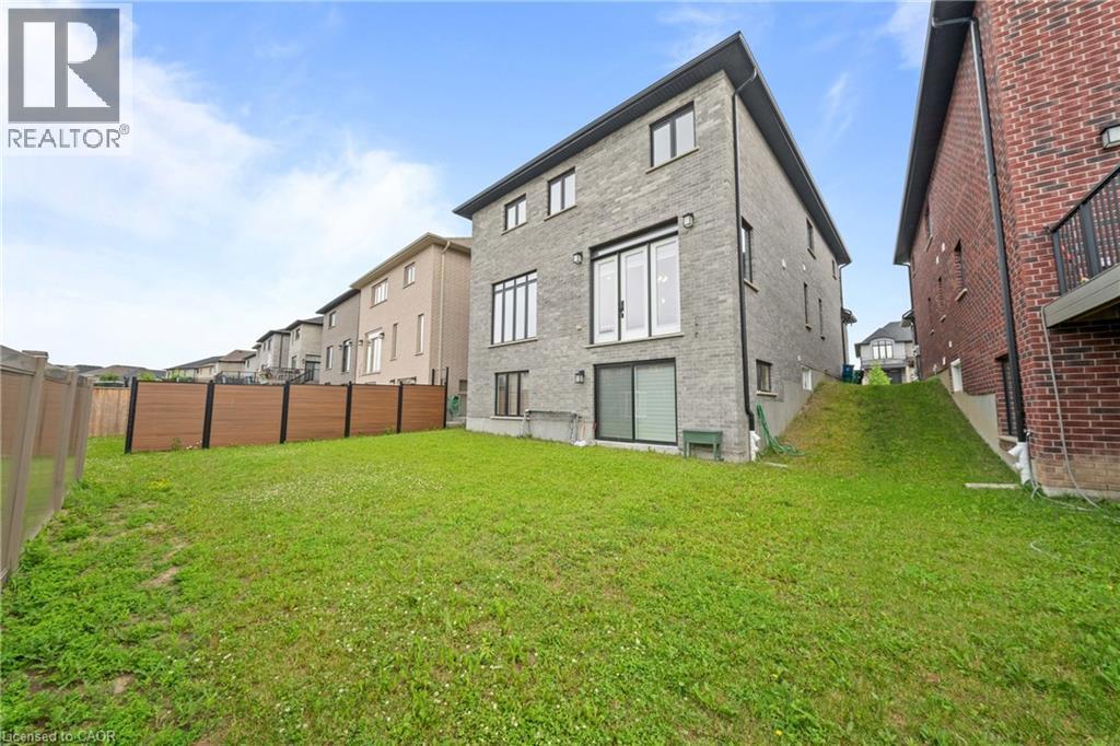 Spacious backyard featuring a sloped lawn and a composite privacy fence - 130 Pondcliffe Drive, Kitchener, ON - Outdoor