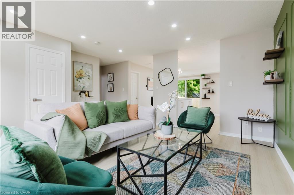 Recessed ceiling lighting, wood-finish flooring, accent wall paneling, and an open layout - 67 Kinzie Avenue, Kitchener, ON - Indoor Photo Showing Living Room