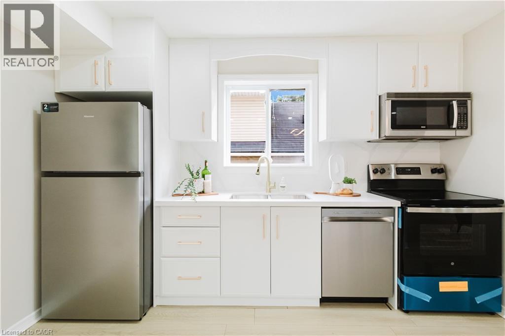 White cabinetry with gold-tone hardware, stainless steel appliances, and a light wood-finish floor - 67 Kinzie Avenue, Kitchener, ON - Indoor Photo Showing Kitchen