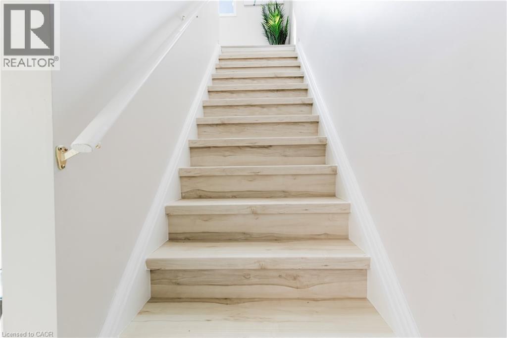 Staircase featuring wood-finish treads and risers, a white handrail, and brass-finish brackets - 67 Kinzie Avenue, Kitchener, ON - Indoor Photo Showing Other Room