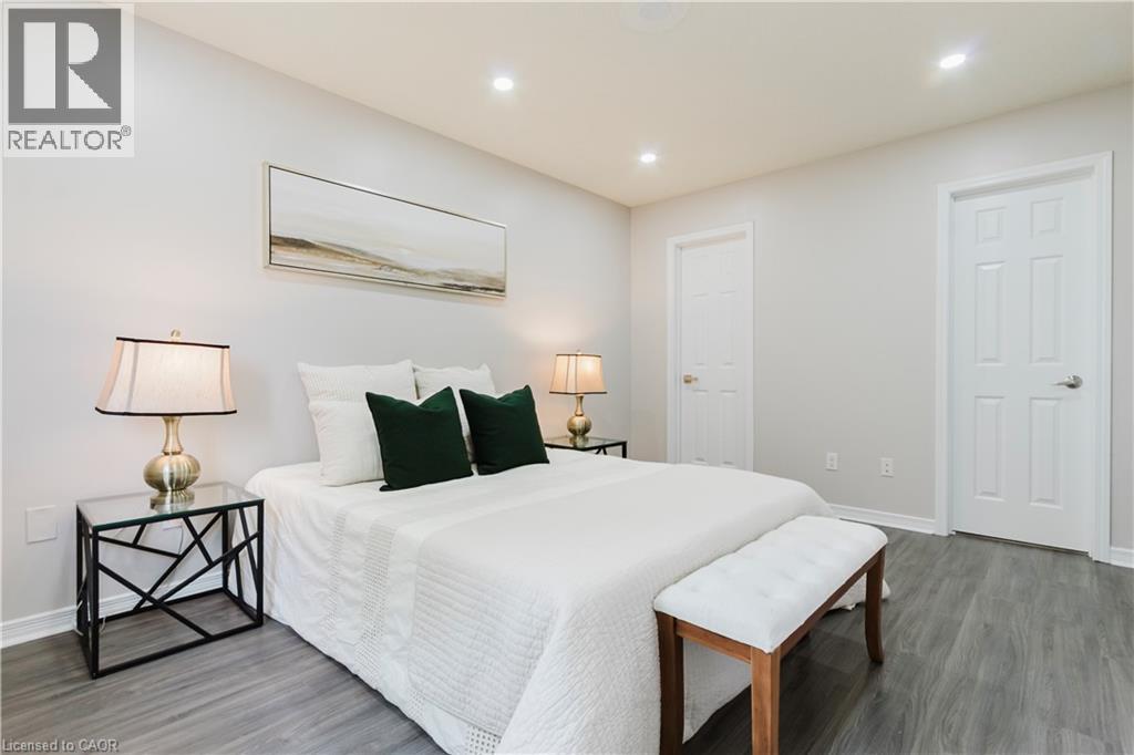 Neutral wall color, recessed ceiling lights, wood-finish flooring, and white paneled doors - 67 Kinzie Avenue, Kitchener, ON - Indoor Photo Showing Bedroom