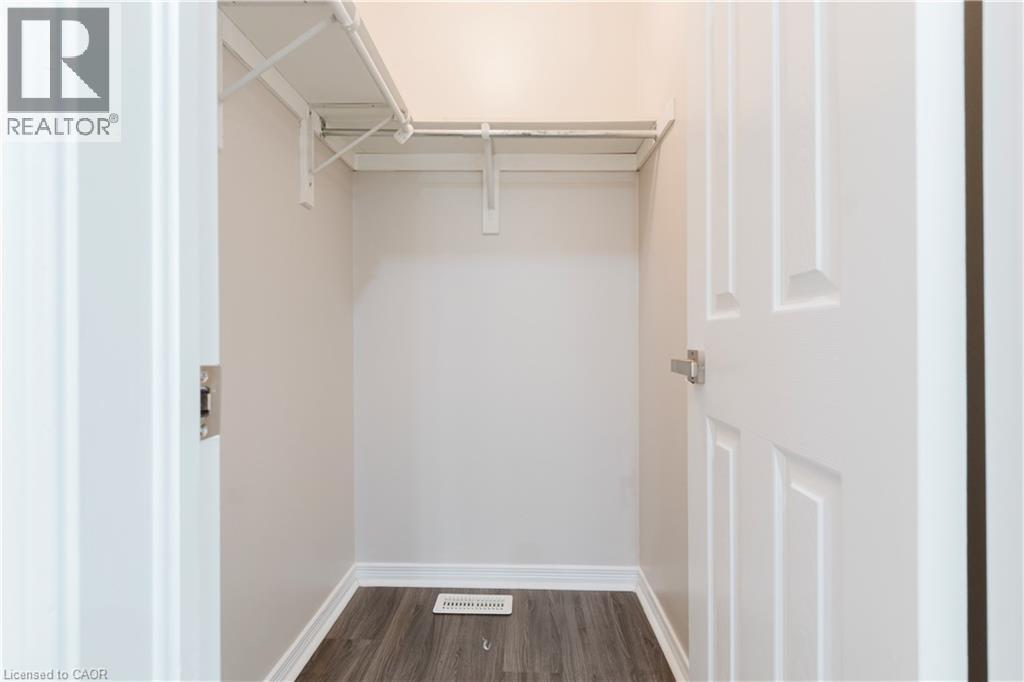 Closet with white wire shelving, hanging rod, wood-finish flooring, and white baseboards - 67 Kinzie Avenue, Kitchener, ON - Indoor With Storage