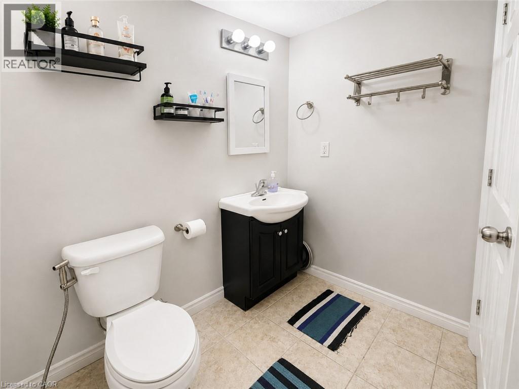 White toilet with bidet attachment, vanity with sink, wall-mounted mirror, and tile flooring - 67 Kinzie Avenue, Kitchener, ON - Indoor Photo Showing Bathroom
