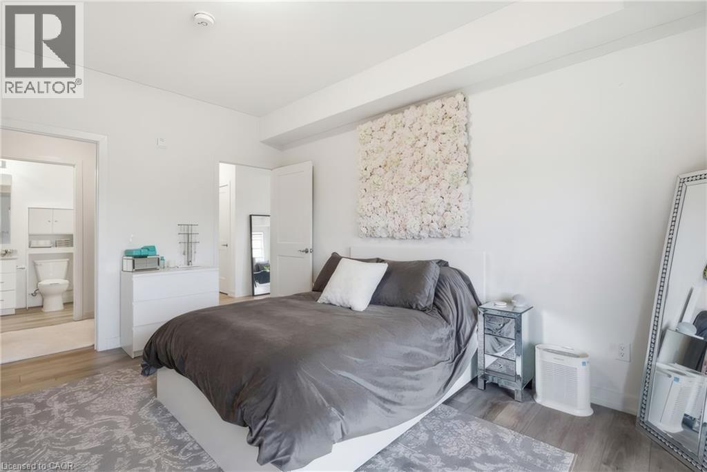 Light wood-finish flooring with white walls and trim, featuring a partial bathroom entry - 251 Northfield Drive E Unit# 312, Waterloo, ON