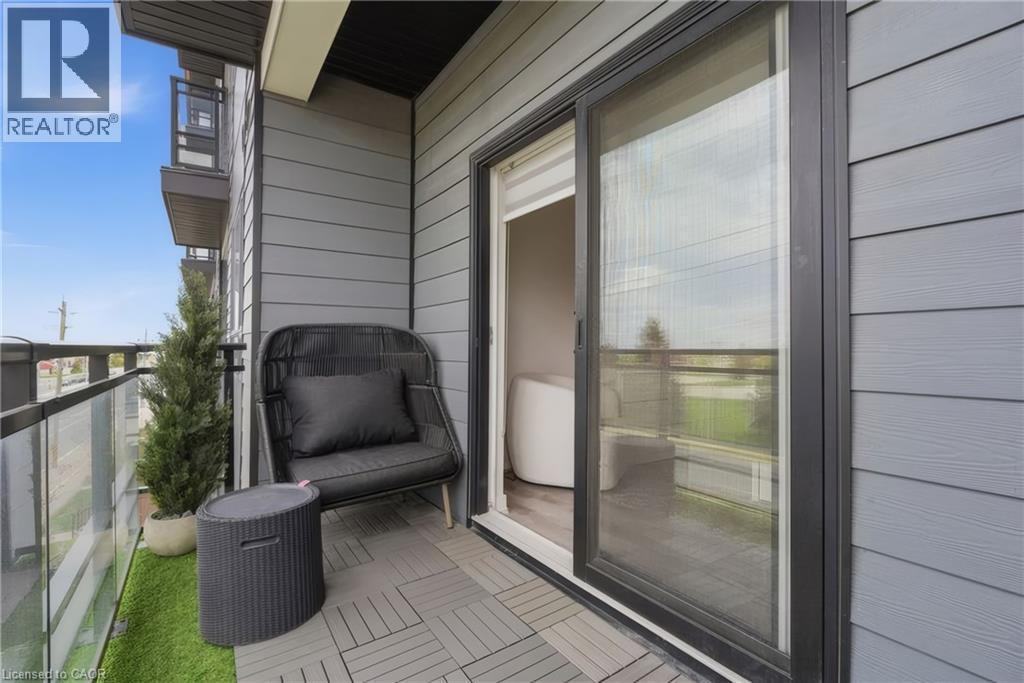 Balcony featuring gray plank-style flooring, glass and metal railing, and gray siding exterior - 251 Northfield Drive E Unit# 312, Waterloo, ON