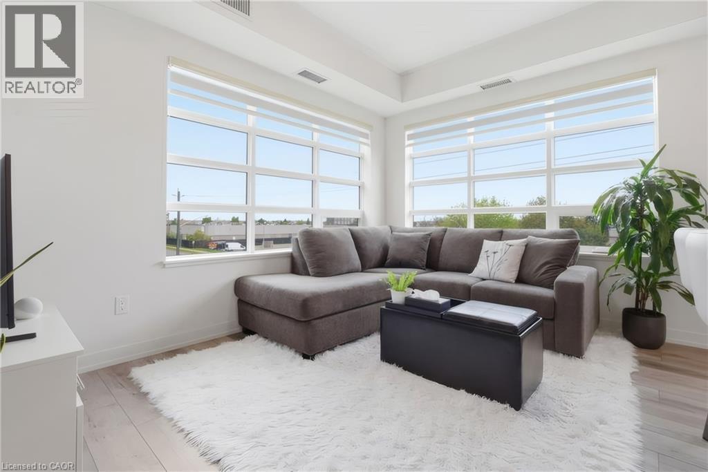 Expansive windows with roller shades, light wood-finish flooring, recessed ceiling, and white wall finishes - 251 Northfield Drive E Unit# 312, Waterloo, ON