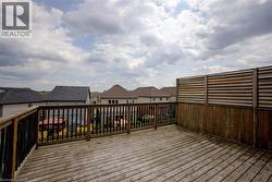 Spacious outdoor deck with wood flooring, wood railing with black spindles, and a slatted wood privacy screen - 