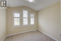 Vaulted ceiling, three windows with white plantation shutters, neutral wall color, and carpet flooring - 