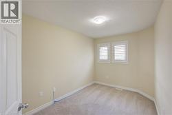 Light neutral wall paint, carpeted flooring, overhead flush mount light, two windows with plantation shutters, and a white interior door - 