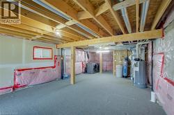Unfinished basement with exposed ceiling joists, insulation, utility hookups, and a window - 