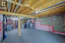 Unfinished basement with exposed wooden joists and structural beams, insulated walls, and concrete flooring - 