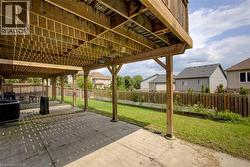 Expansive outdoor space featuring a covered concrete patio, wood fencing, and a grassy area - 
