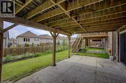 Covered concrete patio with wood structural beams and posts, leading to a grassy yard with a wood fence - 