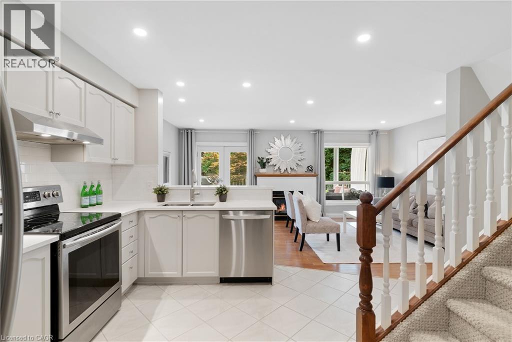 Open-concept layout featuring a kitchen with stainless steel appliances, white cabinetry, and light-toned tile flooring - 711 Angler Way, Waterloo, ON - Indoor Photo Showing Kitchen With Upgraded Kitchen