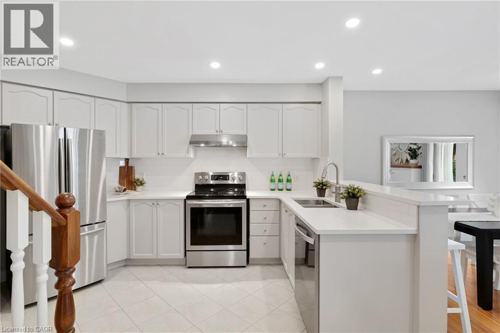 Kitchen featuring white cabinetry, stainless steel appliances, light-toned countertops, tile flooring, and recessed lighting - 711 Angler Way, Waterloo, ON - Indoor Photo Showing Kitchen With Double Sink With Upgraded Kitchen
