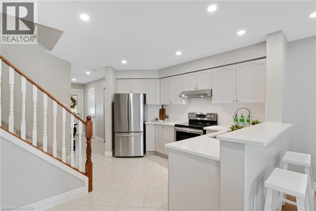 Modern kitchen featuring white cabinetry, stainless steel appliances, tile flooring, and recessed lighting - 711 Angler Way, Waterloo, ON - Indoor Photo Showing Kitchen With Upgraded Kitchen