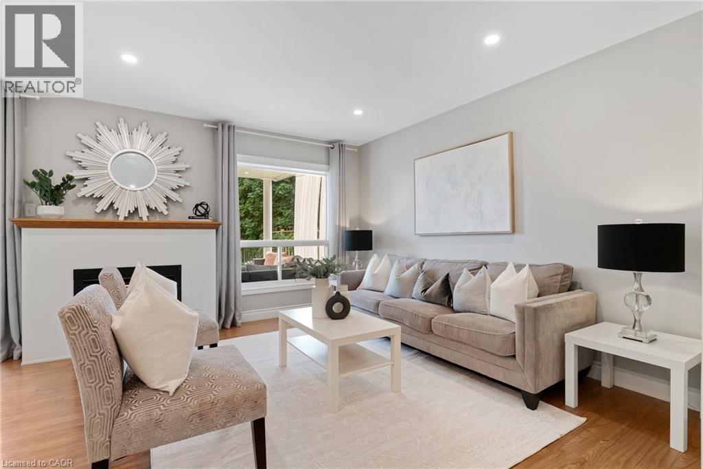 Recessed lighting, wood-finish flooring, white fireplace, and a large window - 711 Angler Way, Waterloo, ON - Indoor Photo Showing Living Room