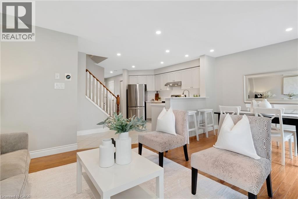Open-concept living area featuring wood-finish flooring, recessed lighting, and a white painted staircase with wood handrail - 711 Angler Way, Waterloo, ON - Indoor Photo Showing Living Room
