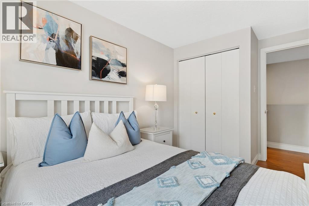 White headboard, neutral wall color, bi-fold closet doors, and wood-finish flooring - 711 Angler Way, Waterloo, ON - Indoor Photo Showing Bedroom