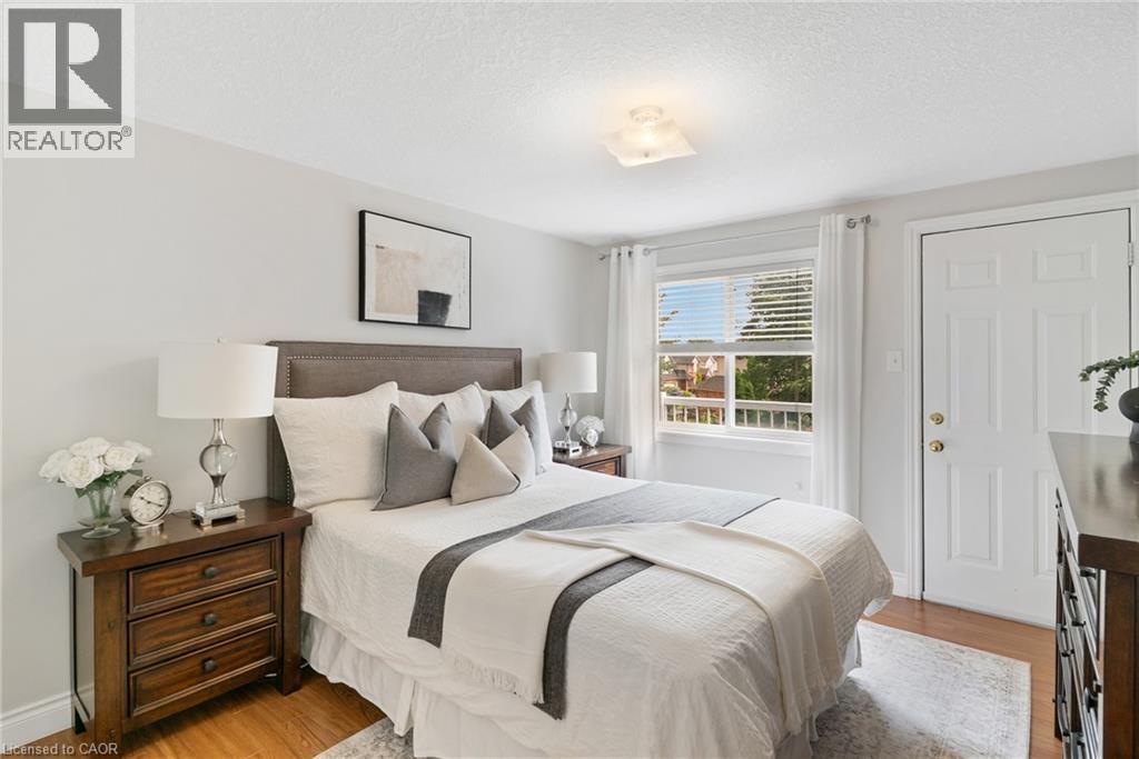 Hardwood flooring, light-toned walls, a window with horizontal blinds, a white paneled door, and a flush mount ceiling light fixture - 711 Angler Way, Waterloo, ON - Indoor Photo Showing Bedroom