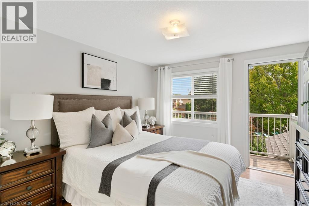 Hardwood-finish flooring, a contemporary ceiling light fixture, and an exterior balcony with white railings - 711 Angler Way, Waterloo, ON - Indoor Photo Showing Bedroom