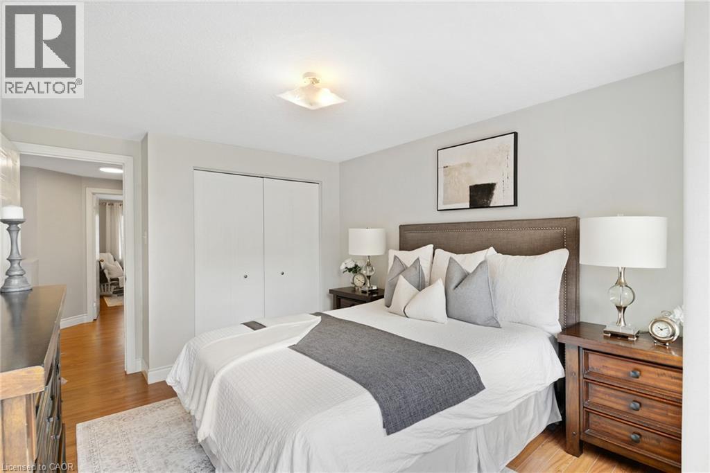 Wood-finish flooring, light gray wall paint, and a built-in closet with bi-fold doors - 711 Angler Way, Waterloo, ON - Indoor Photo Showing Bedroom