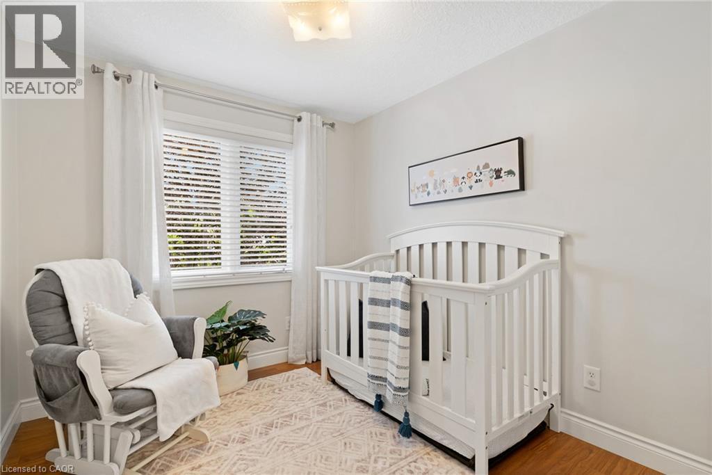 Recessed window with white blinds, wood-finish flooring, white baseboards, and a flush mount ceiling light - 711 Angler Way, Waterloo, ON - Indoor Photo Showing Bedroom
