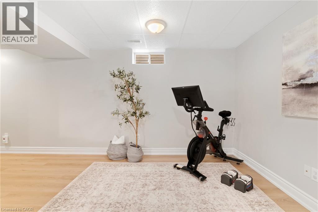 Wood-finish flooring, drop ceiling with recessed lighting, and a window - 711 Angler Way, Waterloo, ON - Indoor Photo Showing Gym Room