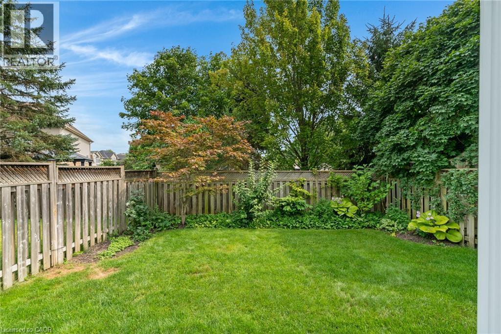 Expansive green lawn with mature perimeter trees and a wood fence with lattice accents - 711 Angler Way, Waterloo, ON - Outdoor
