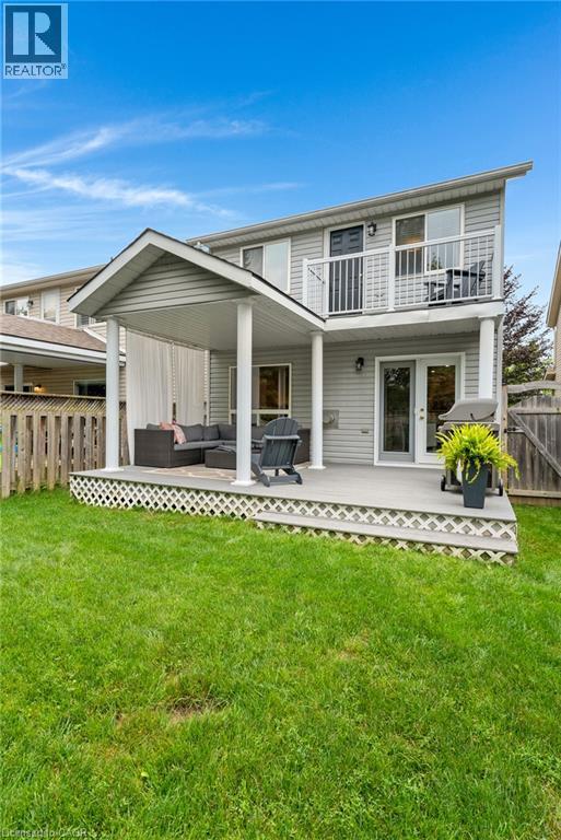 Spacious backyard featuring a covered patio, upper-level balcony, and expansive lawn - 711 Angler Way, Waterloo, ON - Outdoor With Deck Patio Veranda