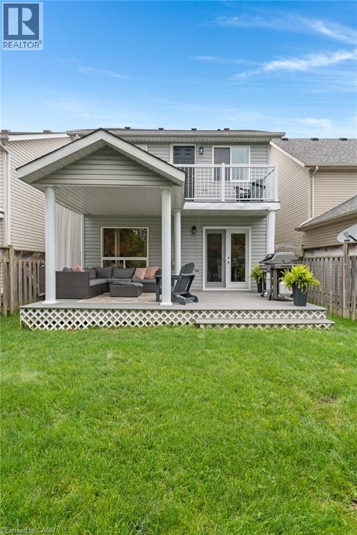Expansive backyard featuring a manicured lawn, a covered patio, an open-air deck, and an upper-level balcony - 711 Angler Way, Waterloo, ON - Outdoor