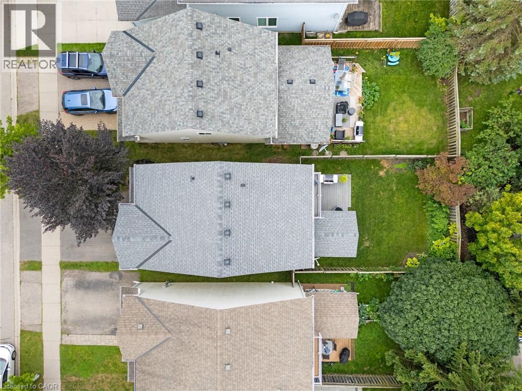 Private backyard space with green lawn, wooden fencing, and mature trees - 711 Angler Way, Waterloo, ON - Outdoor